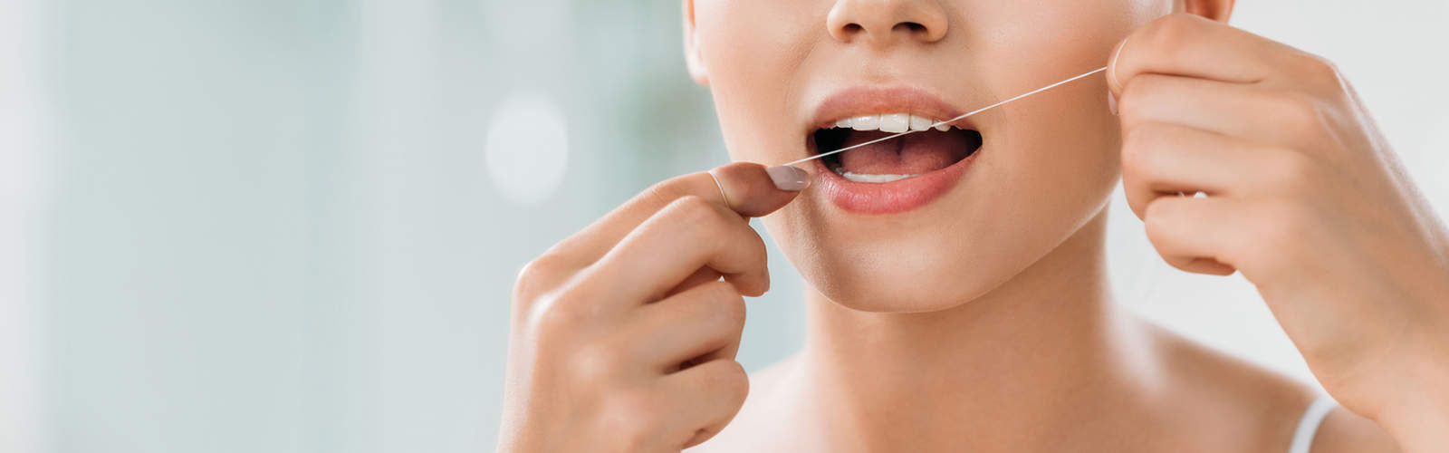 En kvinna använder tandtråd för att undvika tandfyllning